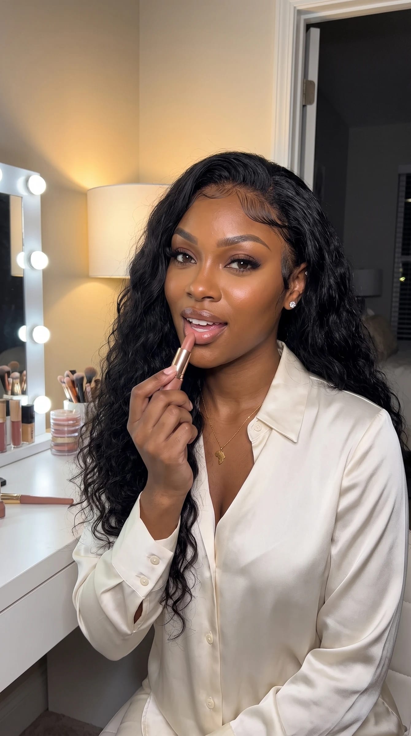 Imani at her vanity holding a nude lipstick, getting ready for date night