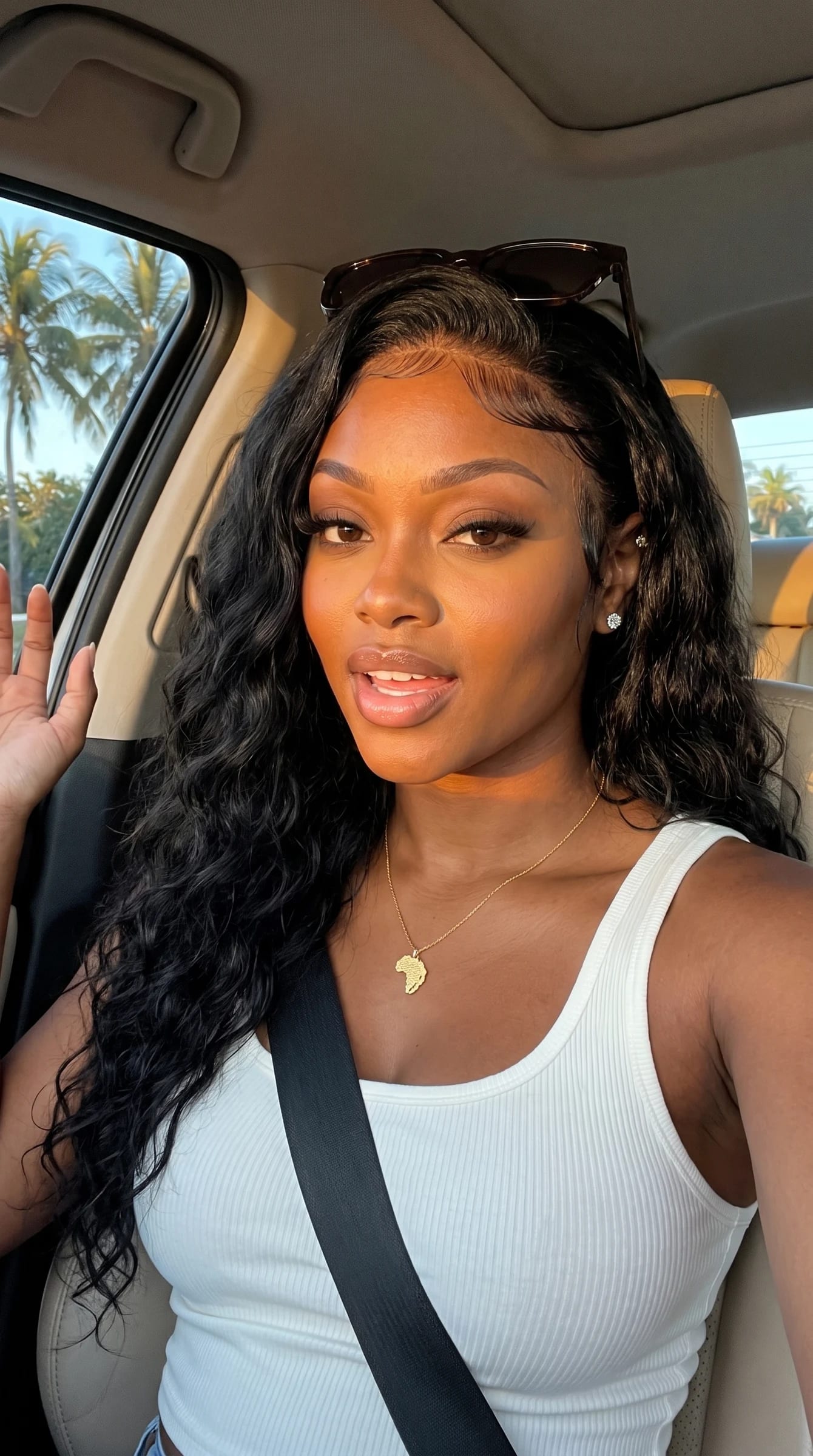 Imani waving from the passenger seat in golden-hour light