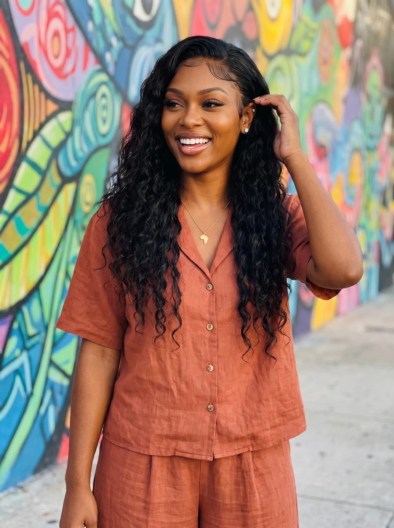 Imani laughing in front of a colorful Wynwood mural in a terracotta linen set